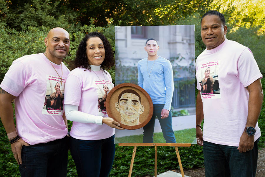 Robby’s family displays the floral portrait they created for him. Left to right: godfather Kevin Brooks, mother Shanteé Broussard and father Robert Barksdale, Sr.